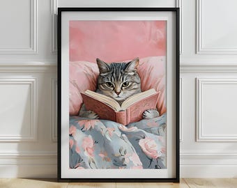 May include: Framed art print of a tabby cat reading a book in bed. The cat is in a pink pillow and under a floral blanket. The book is open, with pages visible. The artwork has a soft, painterly style, with a black frame.