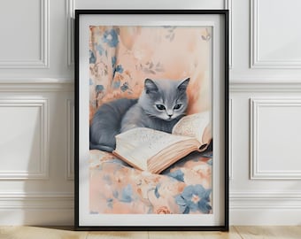 May include: A framed art print depicting a grey cat engrossed in a book. The cat rests on a floral cushion with a peach backdrop and blue flowers. The open book displays text. The artwork is presented in a black frame.
