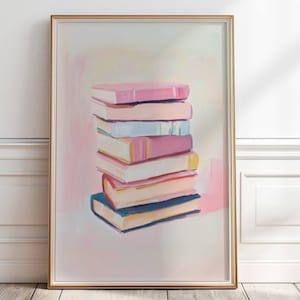 以下が含まれることがあります： パステルカラーの本の山が描かれた、額入りのアートプリント。本はピンク、ブルー、イエローで描かれ、筆致が見えます。アートワークは金色のフレームに入っており、明るい背景に配置されています。