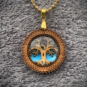 Pu&ograve; includere: Una collana con catena dorata con un ciondolo in legno con un design ad albero della vita blu e marrone.
