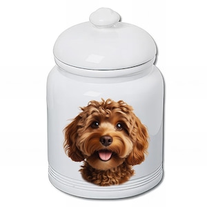 Peut inclure: Pot à friandises pour animaux de compagnie en céramique blanche avec couvercle. Le pot présente une illustration détaillée d'un chien Cavapoo brun et beige avec la langue sortie. Le pot a une finition brillante et des lignes noires à la base.