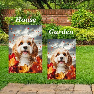Könnte beinhalten: Zwei Gartenflaggen mit einem Cavalier King Charles Spaniel Hund, umgeben von Herbstblättern. Die Flaggen sind mit "House" und "Garden" beschriftet. Der Hund hat braunes und weißes Fell und einen fröhlichen Gesichtsausdruck.