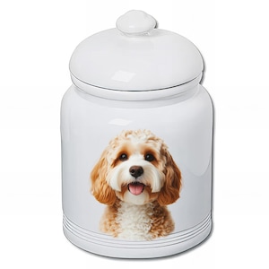 May include: A white ceramic pet treat jar with a lid. The jar features a detailed image of a Cavapoo dog with brown and white fur. The jar has a glossy finish and is designed for storing pet treats.