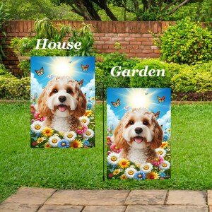 Könnte beinhalten: Zwei Gartenflaggen mit einem lächelnden Hund, blauem Himmel, Schmetterlingen und Blumen. Die Flaggen tragen die Aufschrift "House" und "Garden". Der Hund hat hellbraunes und weißes Fell. Die Flaggen stehen auf einem grünen Rasen.