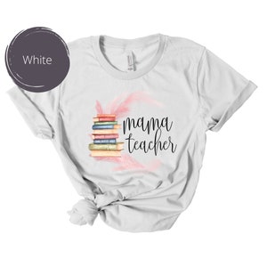 May include: White t-shirt with a stack of books and pink feathers, and the text "mama teacher" printed on the front.