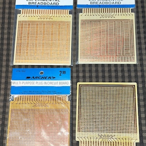 May include: Three Archer brand circuit boards in original blue and white packaging labeled Op-Amp IC Experimental Breadboard, Digital IC Experimental Breadboard, and Multi-Purpose Plug-In Circuit Board, alongside one loose square circuit board.