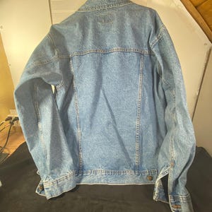 May include: A light blue denim jacket with a button closure and long sleeves.