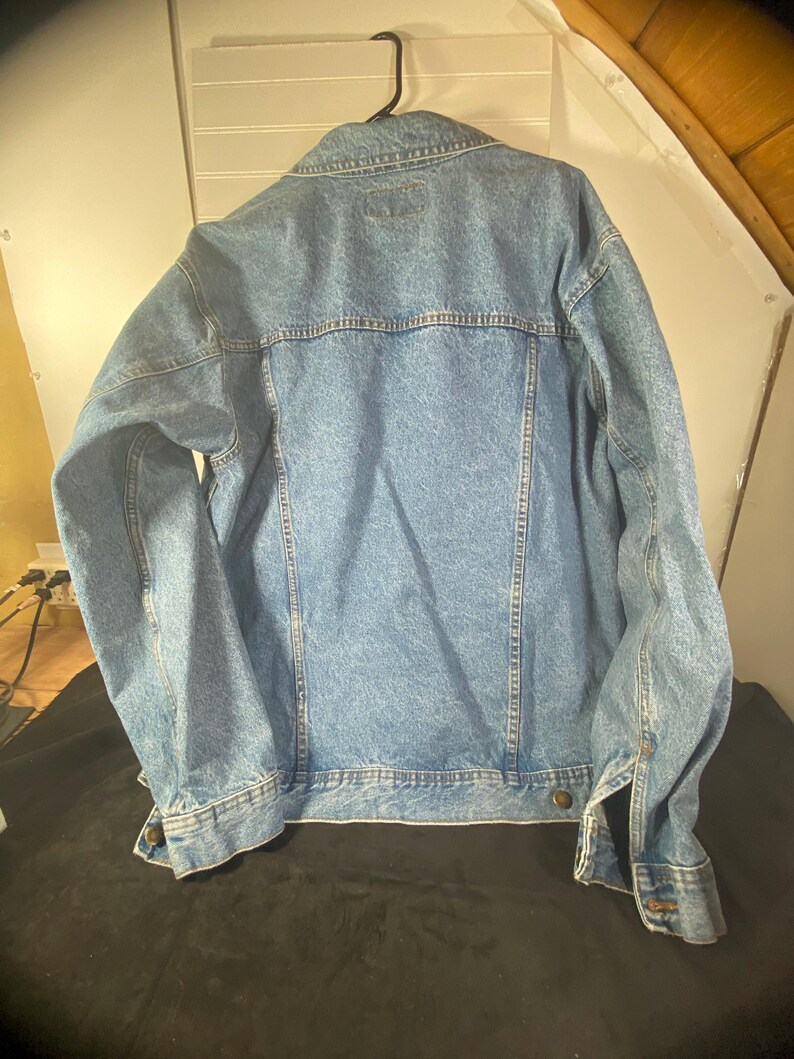 May include: A light blue denim jacket with a button closure and long sleeves.