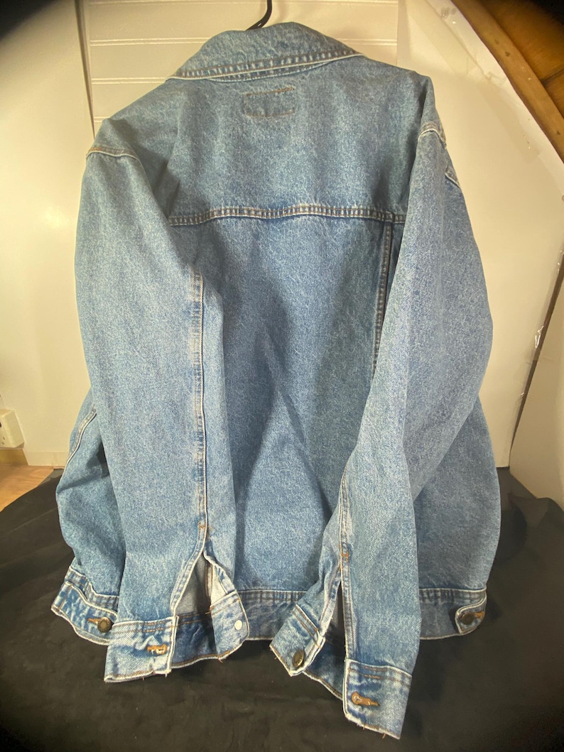 May include: A blue denim jacket with a button-up front and long sleeves. The jacket has a classic design with two pockets on the chest and two pockets on the hips.
