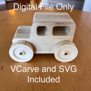 May include: A wooden toy car with a light wood finish. The car has a rectangular body with two windows and four wheels. The text "Digital File Only" and "VCarve and SVG Included" is printed below the car.