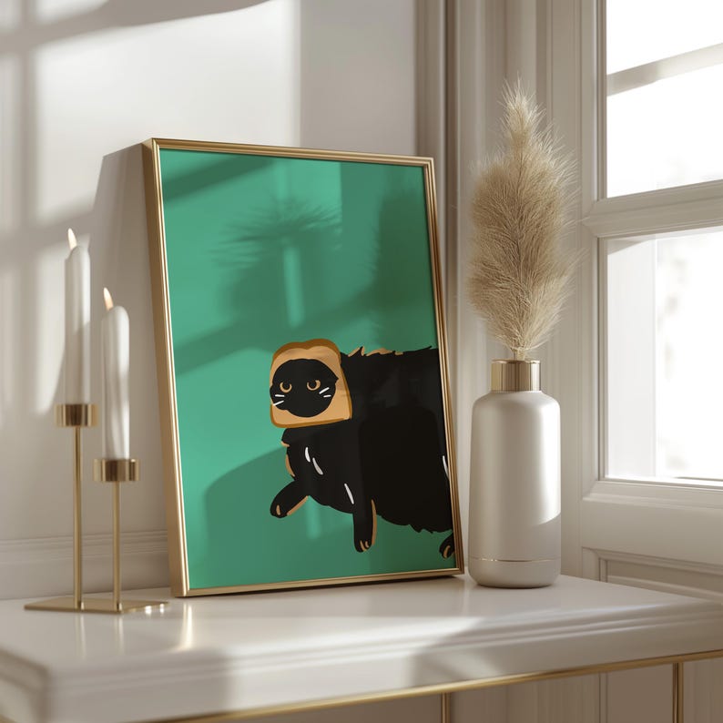 May include: A framed print of a black cat wearing a slice of bread on its head. The cat is looking to the left, and the background is a teal green colour.