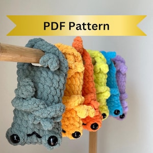 May include: A set of six crocheted plush toys in various colors, including teal, yellow, orange, red, blue, and purple. The toys are hanging from a wooden dowel rod and have large black eyes. The toys are all in the shape of a small animal with a curled tail.