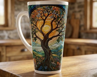 May include: A tall white ceramic mug featuring a colorful stained glass style design of a tree with a central sun, surrounded by green hills and flowers. The handle is white and curved, and the mug has a smooth, cylindrical shape.