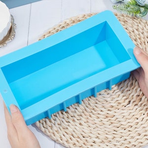 May include: A light blue silicone mold for making soap or other crafts. The mold is rectangular with a smooth, flat surface and a slightly raised edge.