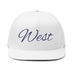 May include: A white flat-brimmed cap featuring the word "West" embroidered in dark blue script. The cap has a structured crown and a flat peak, with a green underside.