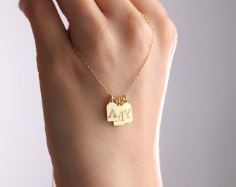 May include: A gold chain necklace with three small rectangular tags, each with a letter of the name "AMY" engraved on it.