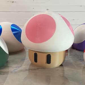 May include: A set of five 3D printed mushroom-shaped figurines. The figurines are painted in various colors, including green, blue, purple, pink, and white.