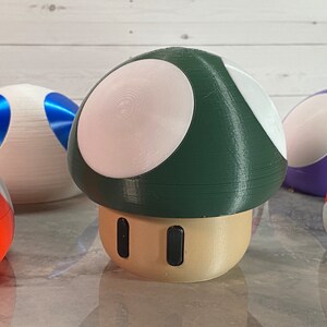 May include: A green and white mushroom-shaped toy with a brown base and two black dots on the front. The mushroom is surrounded by other colorful mushroom-shaped toys.
