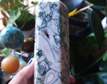 Pode incluir: Uma ponta de cristal de ágata branca e verde com forma facetada. O cristal tem um padrão natural e orgânico de verde e branco.
