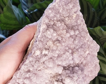 May include: A large, irregularly shaped amethyst crystal with a purple and white color. The crystal has a rough, textured surface and is covered in small, white crystals.