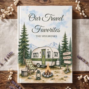 May include: A hardcover book titled Our Travel Favorites The Spelbrinks featuring a watercolor illustration of a vintage camper, a campfire, a folding chair, pine trees, mountains, and a wooden signpost with the text Happy Travels.