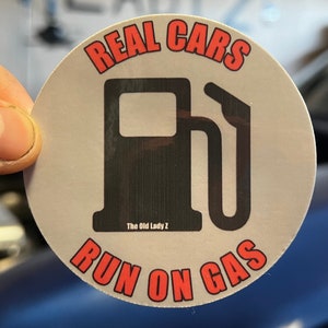 May include: A round sticker with a gas pump graphic and the text "REAL CARS RUN ON GAS" in red. The text "The Old Lady Z" is printed below the gas pump.