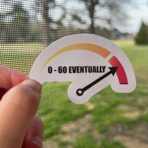 May include: A white sticker with a speedometer design. The needle points to the right and reads "0-60 EVENTUALLY".