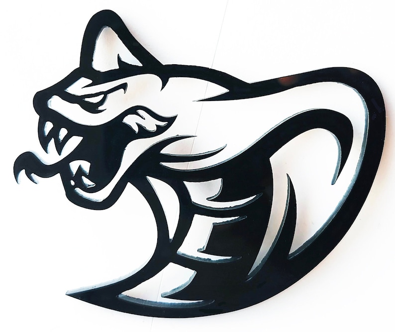 Op de afbeelding: Zwarte metalen wandkunst met een gestileerde kattenkop met open mond, scherpe tanden en een agressieve uitdrukking. Het ontwerp heeft een strakke, moderne esthetiek, geschikt voor woondecoratie of autothema's.