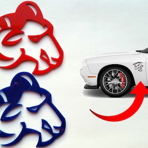 May include: Two ram head decals, one red and one blue, with a white background. The decals are shown next to a white Dodge Challenger with a black ram head decal on the side.
