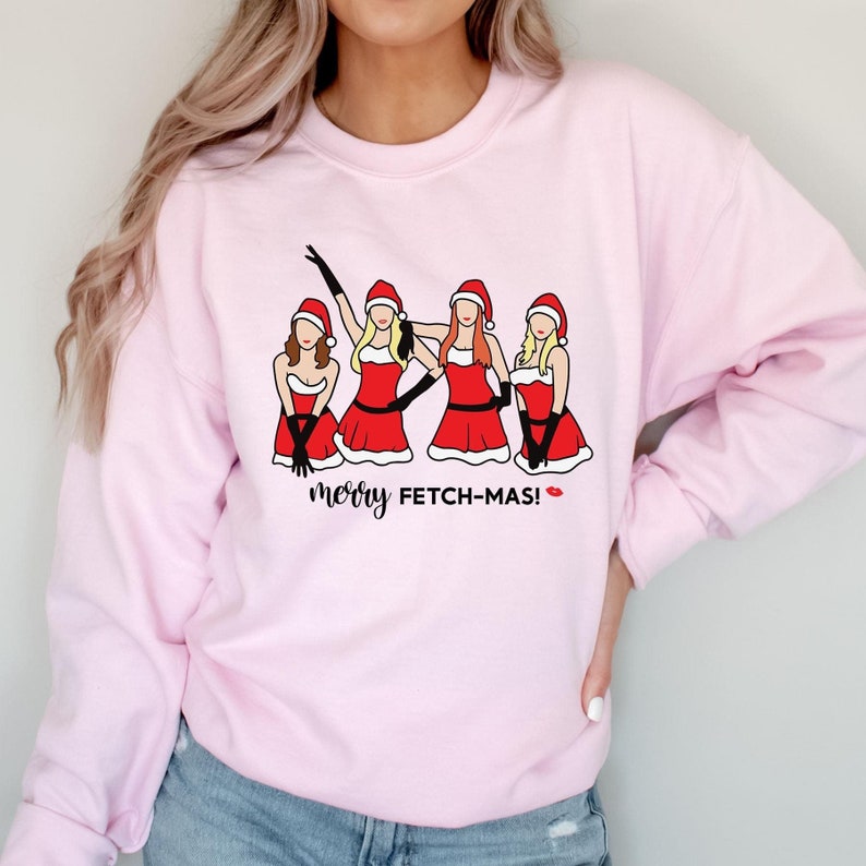 May include: Pink sweatshirt with a graphic of four women dressed as Santa Claus with the text "merry FETCH-MAS!" printed on the front.