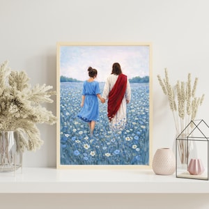 May include: Framed art print depicting two figures walking through a field of blue flowers. One figure wears a blue dress, the other a white robe and red sash. The artwork is displayed on a white shelf with decorative elements.