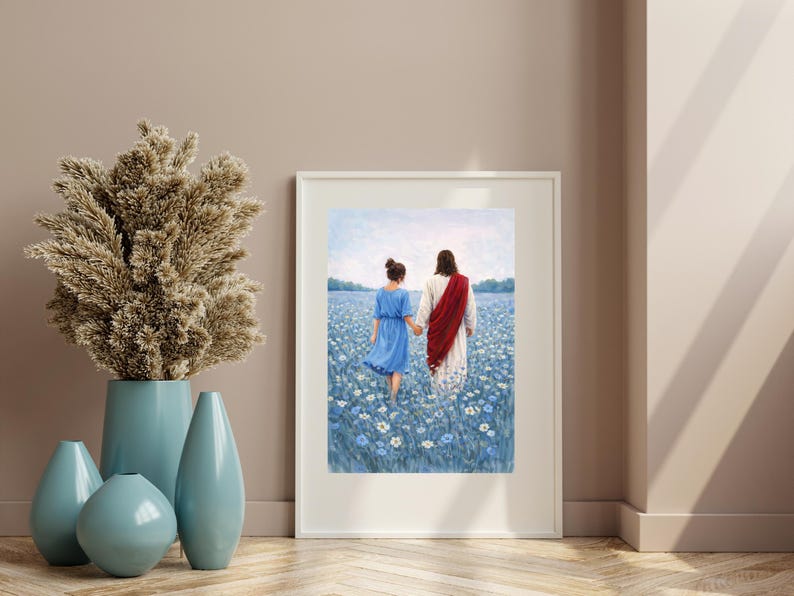 May include: A framed art print depicts two figures walking through a field of blue flowers. One figure wears a blue dress, the other a white robe with a red sash. A tall, dried floral arrangement and blue vases are in the foreground.