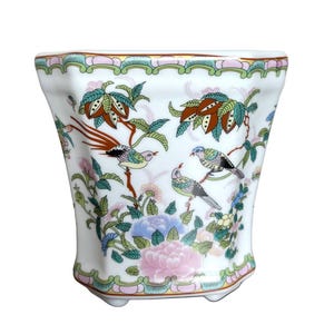 May include: White ceramic planter with a floral and bird design. The planter has a scalloped rim and a hexagonal base.