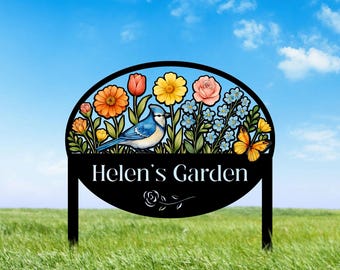 Könnte beinhalten: Schwarzes Metall-Gartenschild mit einem Blauhäher und bunten Blumen. Das Schild trägt die Aufschrift "Helen's Garden".