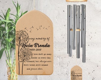 May include: A wooden wind chime with a black and white striped design. The chime has a wooden plaque with the text "In loving memory of Kevin Brenda 1989-2018 Those we love don't go away. They walk beside us every day. Unseen, unheard, but always near. Still loved, still missed and forever dear."