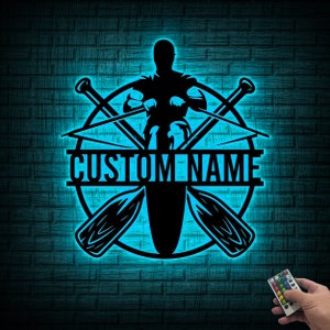 May include: A blue neon sign with a silhouette of a person rowing a boat. The sign has two crossed oars and the text "CUSTOM NAME" in a white banner.