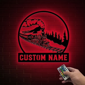 May include: A red illuminated sign with a black silhouette of a train traveling through a forest. The sign has the text "CUSTOM NAME" at the bottom.
