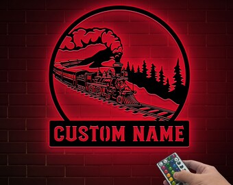 Puede incluir: Un letrero rojo iluminado con una silueta negra de un tren que viaja por un bosque. El letrero tiene el texto "CUSTOM NAME" en la parte inferior.