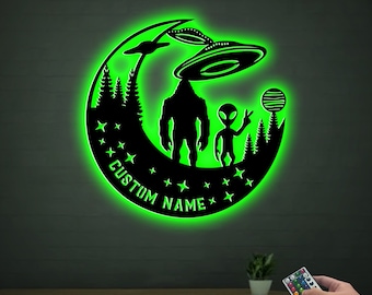May include: Green glowing moon-shaped night light with a silhouette of Bigfoot, an alien, and a UFO. The light has the text "CUSTOM NAME" on the bottom.