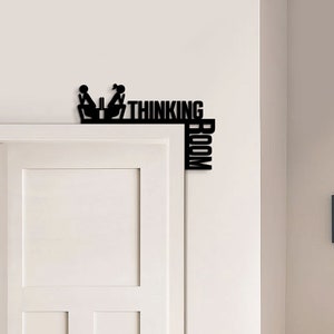 May include: Black metal sign with stick figures of two people sitting at a table. The sign reads "Thinking Room" with the word "Room" vertically oriented.