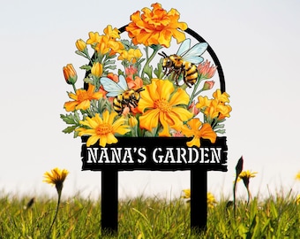 May include: A black metal garden sign with a yellow and white floral design and the text "NANA'S GARDEN".  The flowers are surrounded by bees.