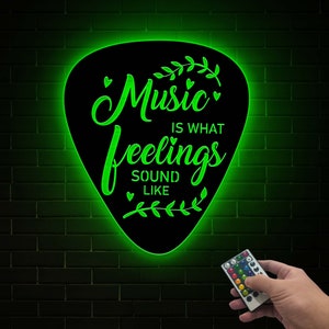 May include: Green neon sign shaped like a guitar pick with the text "Music is what feelings sound like" and a remote control.