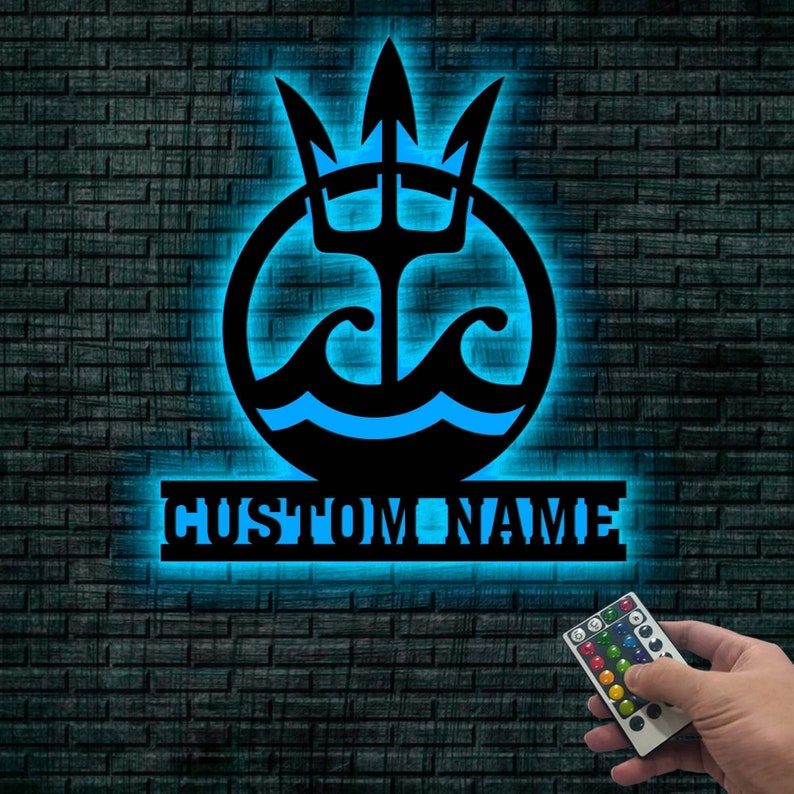 May include: A blue and black metal wall decor with a trident and waves design. The decor has a custom name plate that says "CUSTOM NAME".