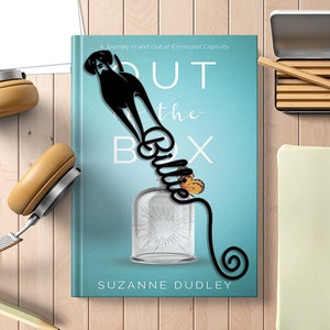 May include: Black metal bookmark shaped like a dog with the word "Billie" curled around its body. The bookmark is on a blue book with the title "Out of the Box" and the author's name "Suzanne Dudley".