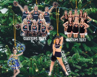 May include: Acrylic Christmas tree ornaments featuring cheerleaders in various poses and uniforms. Each ornament has a gold string for hanging and includes the text "CUSTOM TEXT". The cheerleaders are wearing black, orange, blue, and yellow uniforms.