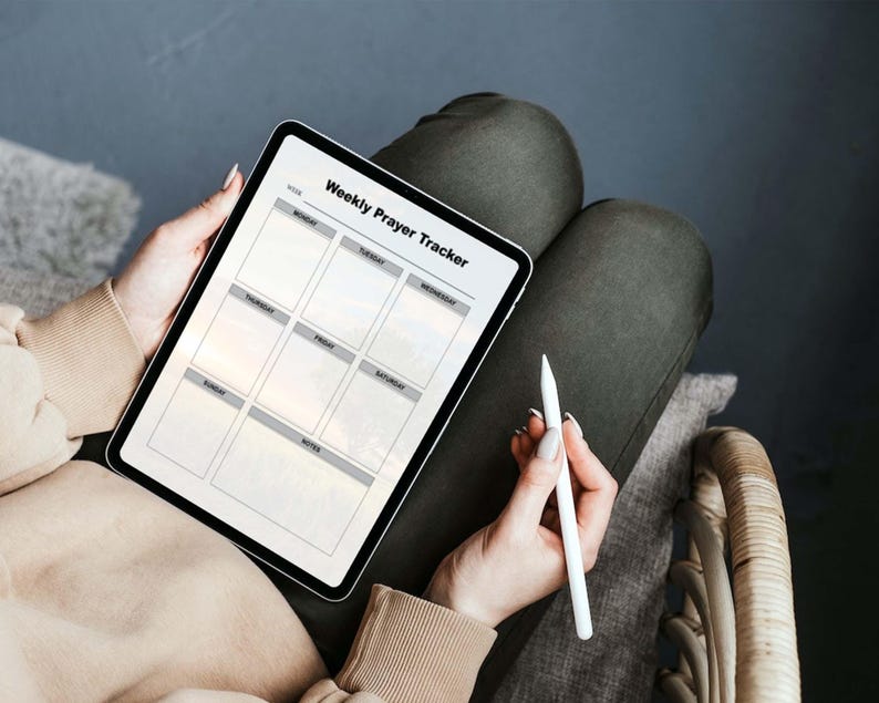 May include: A digital tablet displaying a weekly prayer tracker with a white stylus on a gray surface. The tracker has a grid with days of the week labeled: Monday, Tuesday, Wednesday, Thursday, Friday, Saturday, Sunday, and Notes.