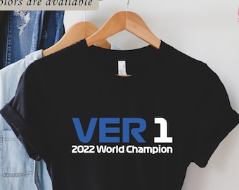 Pode incluir: Camiseta preta com um gráfico azul e branco que diz "VER 1 2022 Campeão Mundial".