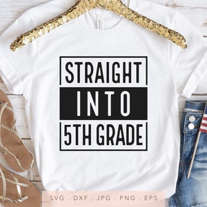 Puede incluir: Camiseta blanca con texto negro que dice "STRAIGHT INTO 5TH GRADE". La camiseta está en una percha y hay sandalias y pantalones cortos de mezclilla en el fondo.