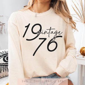 May include: Cream-colored long-sleeve sweatshirt with the text "19 Vintage 76" in black script. The sweatshirt is a neutral color, suitable for various occasions. The design is simple and classic.