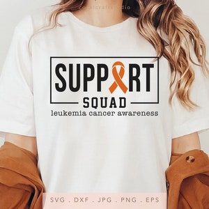 May include: White t-shirt with the text "SUPPORT SQUAD" in a black box with an orange ribbon inside the box. The text "leukemia cancer awareness" is below the box.